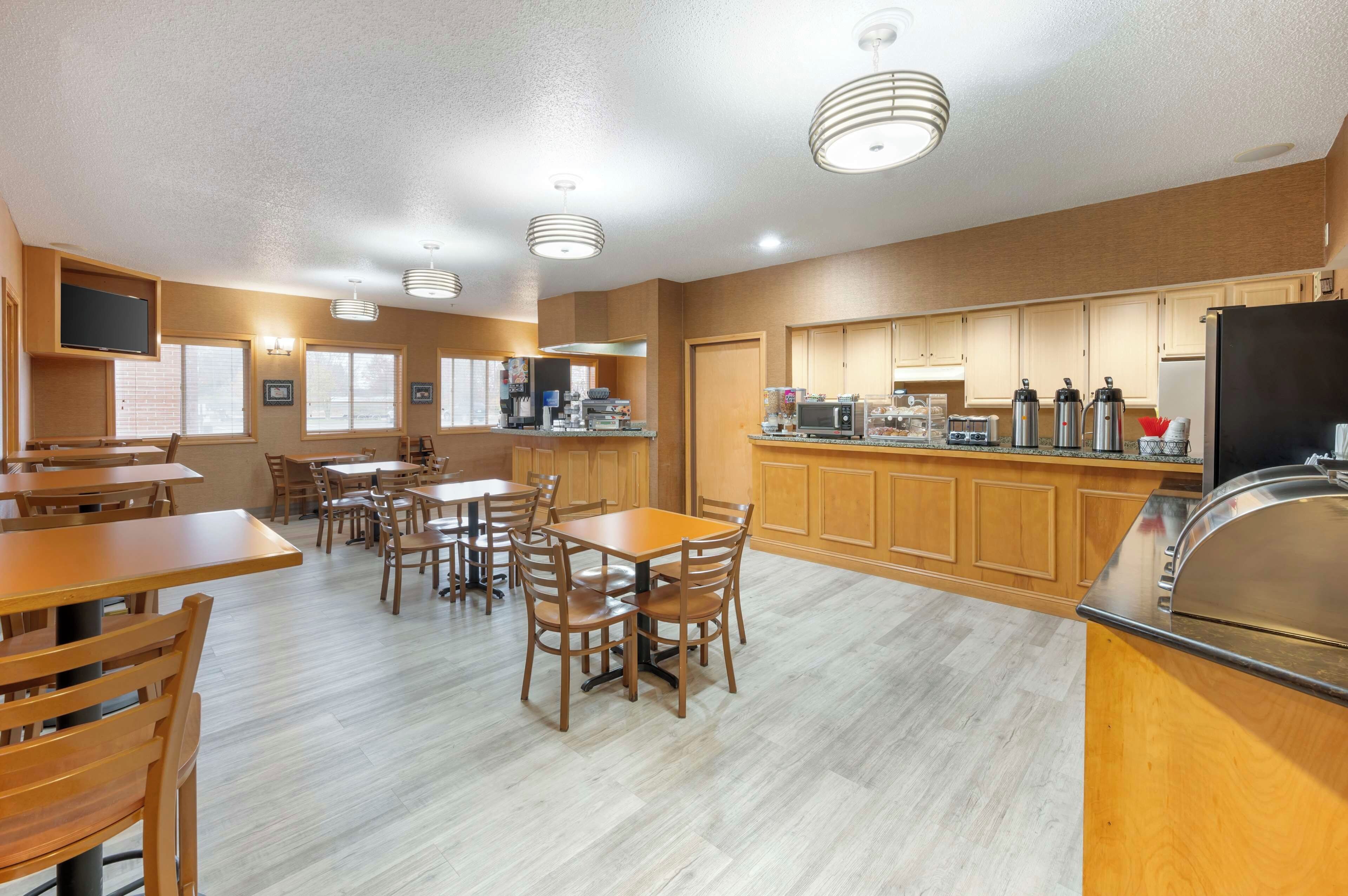 A spacious dining area with wooden tables and chairs, a kitchen with wooden cabinets, and a large refrigerator.
