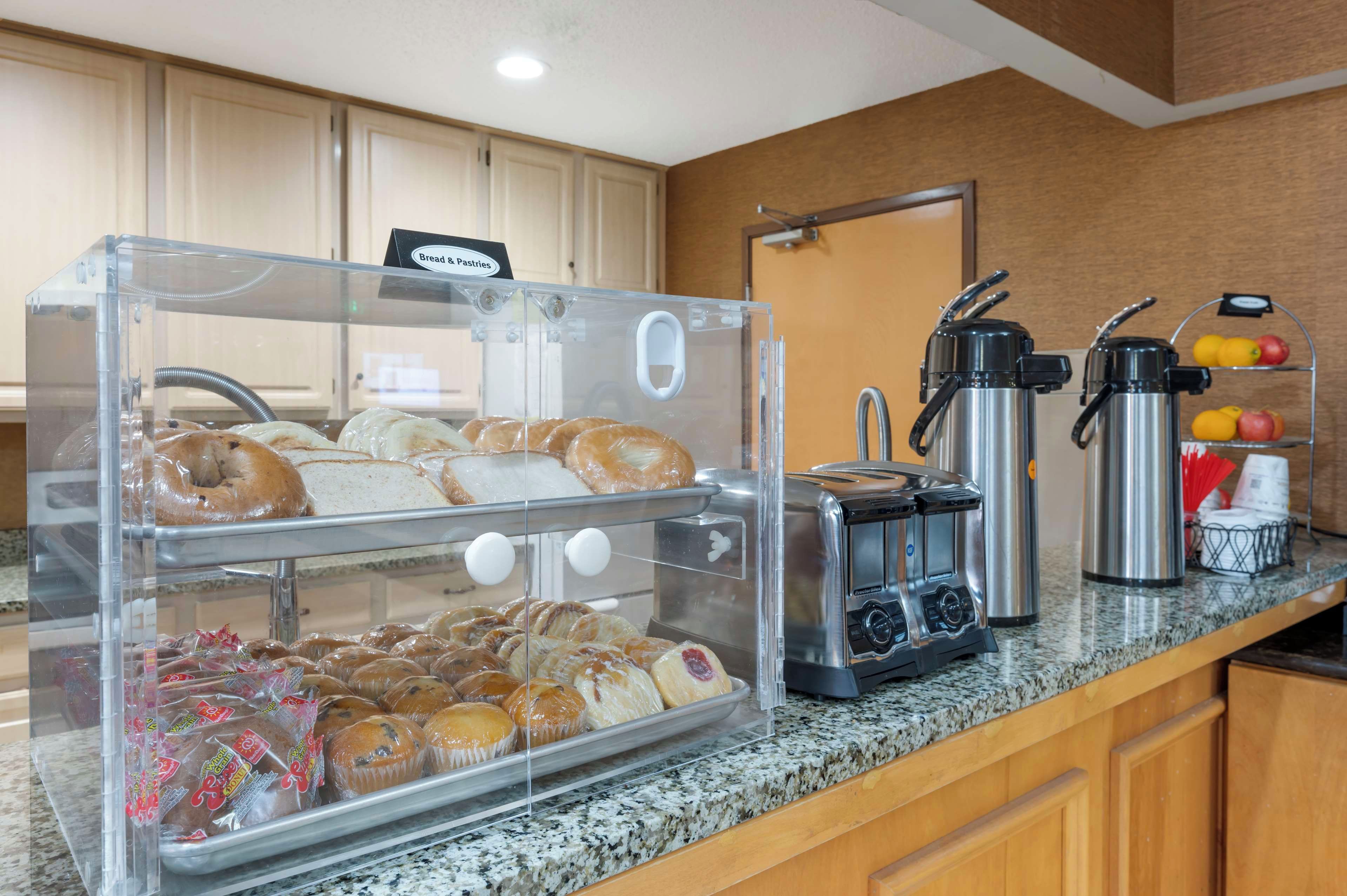 A breakfast buffet with bread, pastries, and a coffee station.