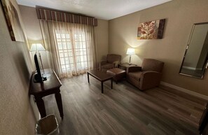 A hotel room with a wooden floor, two armchairs, a sofa, a small table, a TV, and a lamp. - Best Western Circus City Inn (Peru)
