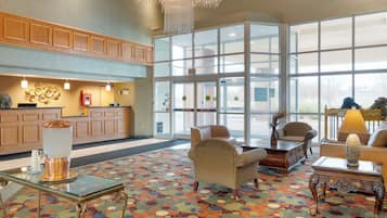 A lobby with a reception desk, seating area, and large windows.