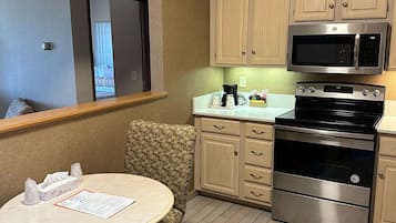 Cocina compacta equipada con microondas, horno y un pequeño comedor con mesa y silla.