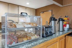 Un buffet de petit-déjeuner comprenant du pain, des viennoiseries et un coin café.