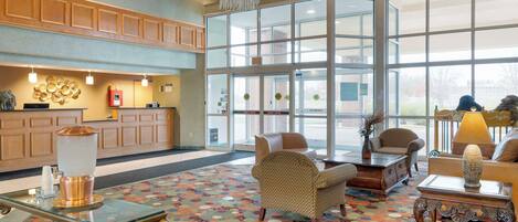 A lobby with a reception desk, seating area, and large windows.