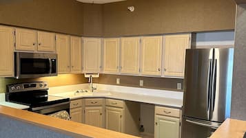 Una cocina con armarios de madera, un refrigerador de acero inoxidable, un microondas y un horno.