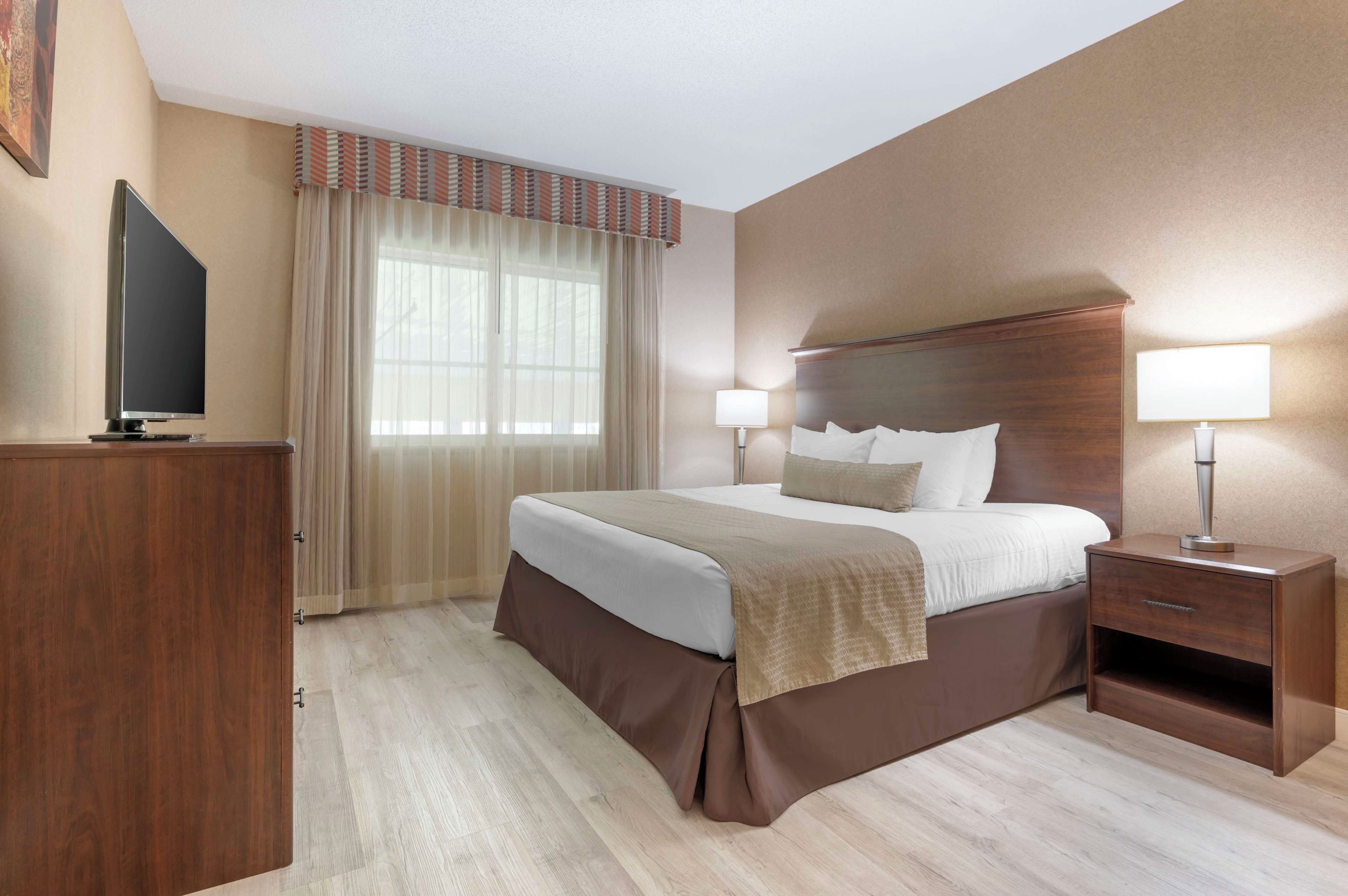 A hotel room with a bed, bedside lamps, a TV, and a desk.
