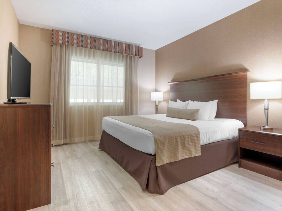 Een hotelkamer met een bed, nachtlampjes, een televisie en een bureau.
