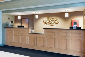 A reception desk with a wooden panel design, a wall-mounted decorative plate arrangement, and a red self-service kiosk. - Best Western Circus City Inn (Peru)