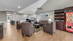 A modern living room with a sofa set, coffee table, and a vending machine. - Quality Inn Laurinburg (Laurinburg)