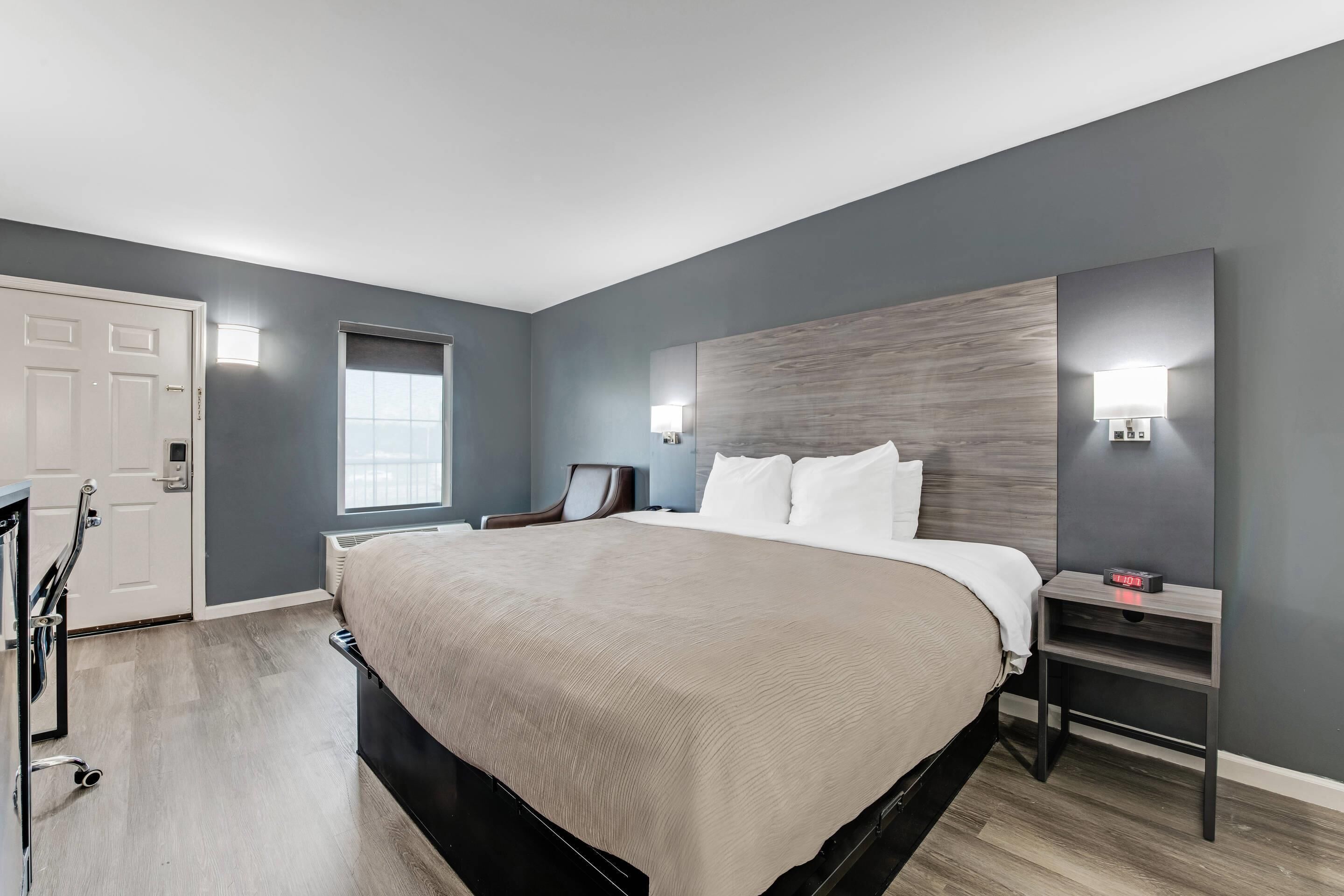 Une chambre à coucher moderne avec un grand lit, une table de chevet, une chaise et une porte.