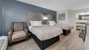 A hotel room with two beds, a chair, a desk, and a kitchenette. - Quality Inn Laurinburg (Laurinburg)