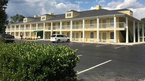 A yellow motel with multiple balconies and a parking lot.