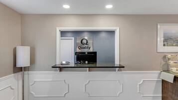 A reception desk with a 'Quality by Choice Hotels' sign, a phone, and a small counter.