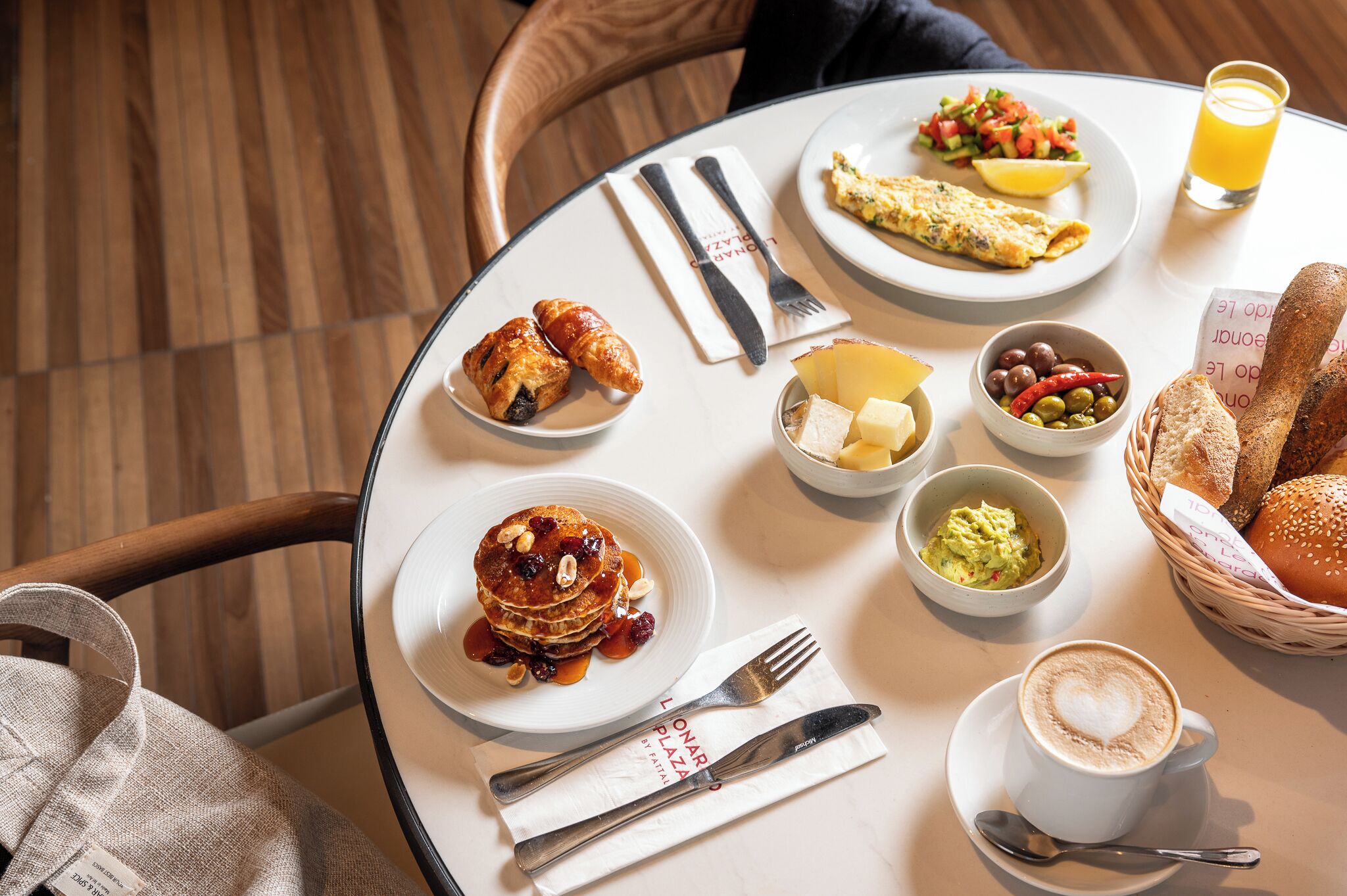 A breakfast setting with pancakes, eggs, toast, and coffee on a round table.
