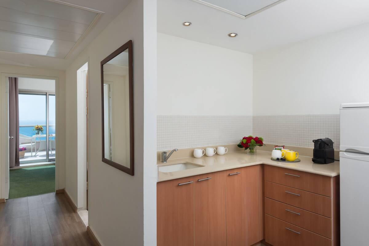 A modern kitchen with a large mirror, a sink, and wooden cabinets.
