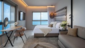 A modern hotel room with a large bed, a desk, and a view of the sea. - Leonardo Plaza Haifa (Haifa)