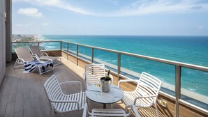 A balcony with white chairs, a table with a bottle and glasses, and a view of the ocean. - Leonardo Plaza Haifa (Haifa)