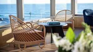 A balcony with wicker chairs, a round table, and a view of the ocean. - Leonardo Plaza Haifa (Haifa)