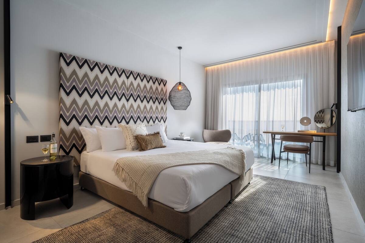 A modern bedroom with a large bed, a desk, and a chair.