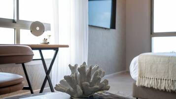A modern bedroom with a bed, a coffee table with a coral sculpture, and a television mounted on the wall.