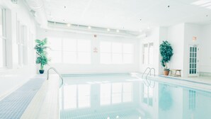 Una piscina interna con acqua cristallina, pavimento piastrellato e piante in vaso.