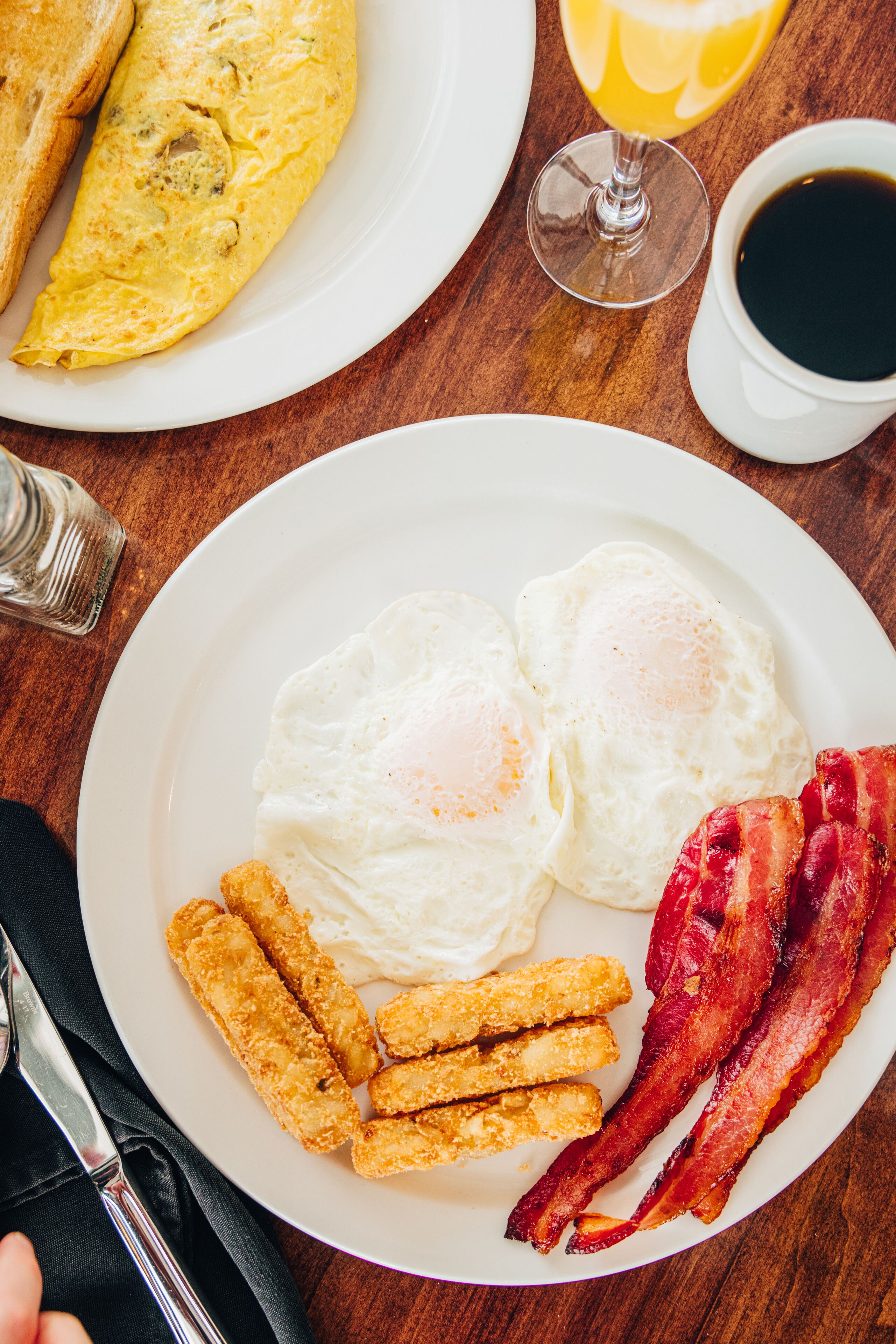 Piatto per la colazione con uova, pancetta e patate tritate su un tavolo di legno.