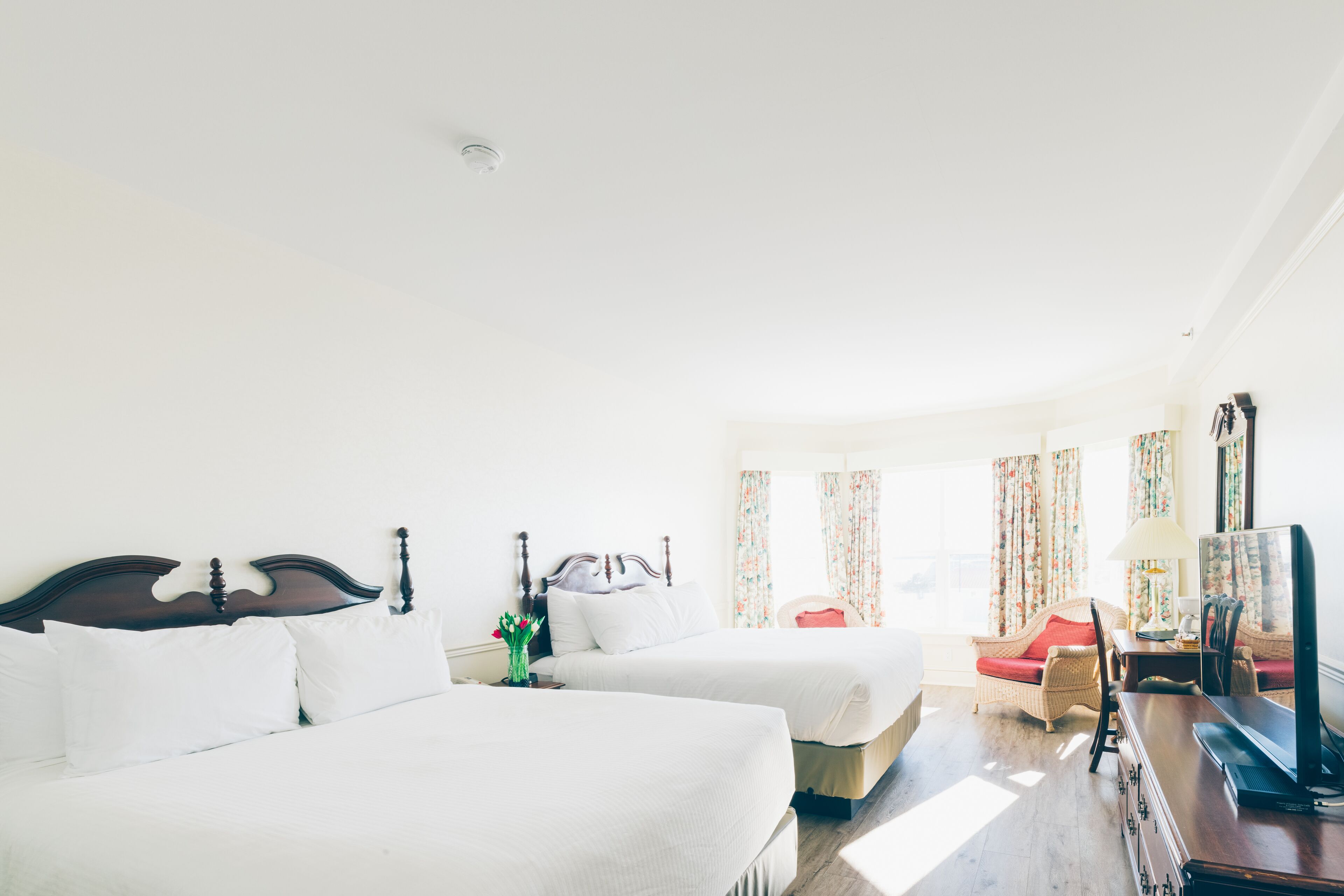 Una habitación de hotel con dos camas, un escritorio con televisor y una silla.