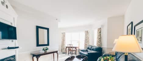 A living room with a fireplace, a black leather sofa, a coffee table, and a lamp.