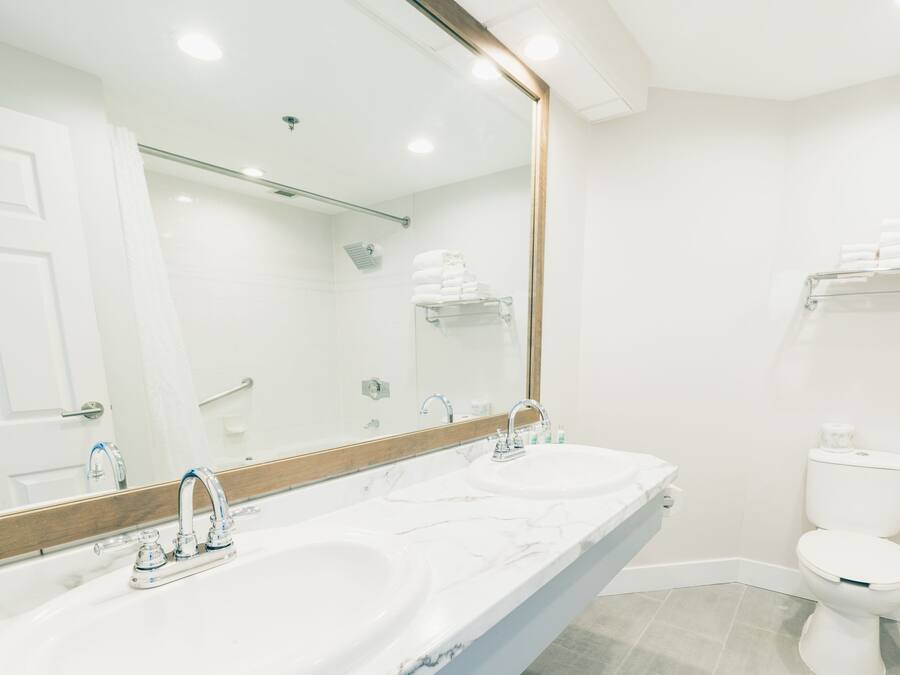 A bathroom with two sinks, a toilet, and a large mirror.