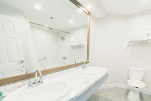 Bathroom features a double sink, large mirror, and toilet with a clean and minimalist design.