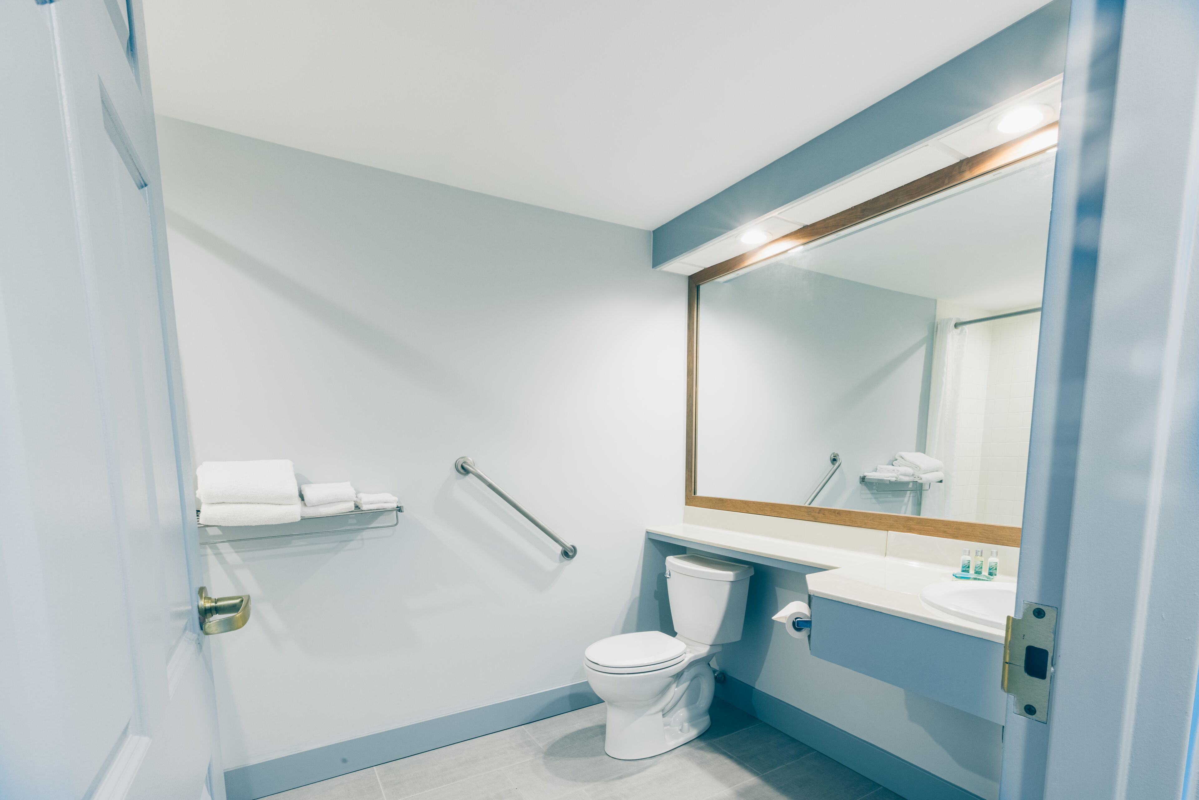 A modern bathroom with a toilet, sink, and handrail.