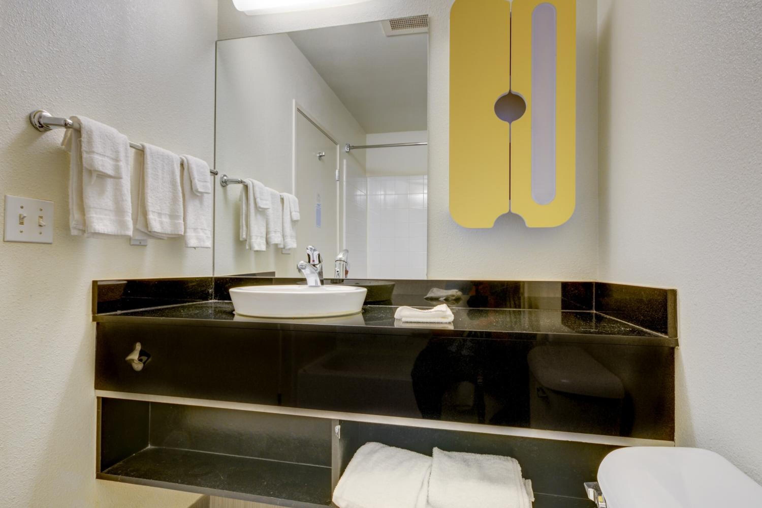 A modern bathroom with a black vanity, white sink, and a large mirror.