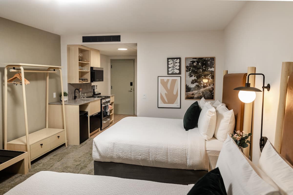 A compact hotel room with a kitchenette, a bed, a desk, and a walk-in closet.