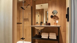 A modern bathroom with a glass shower enclosure, a wooden vanity with a sink, and a mirror.