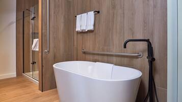 A modern bathroom with a freestanding bathtub, a glass shower enclosure, and a towel rack with two towels.
