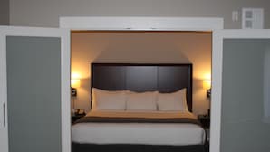 Una camera d'albergo con un letto grande, lampade sui comodini e un armadio.