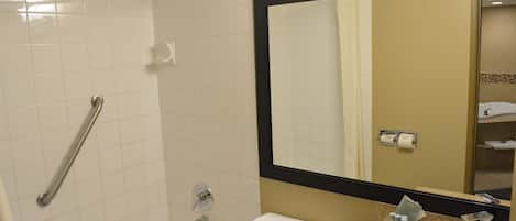 Un baño con bañera, inodoro, lavabo y un espejo grande.