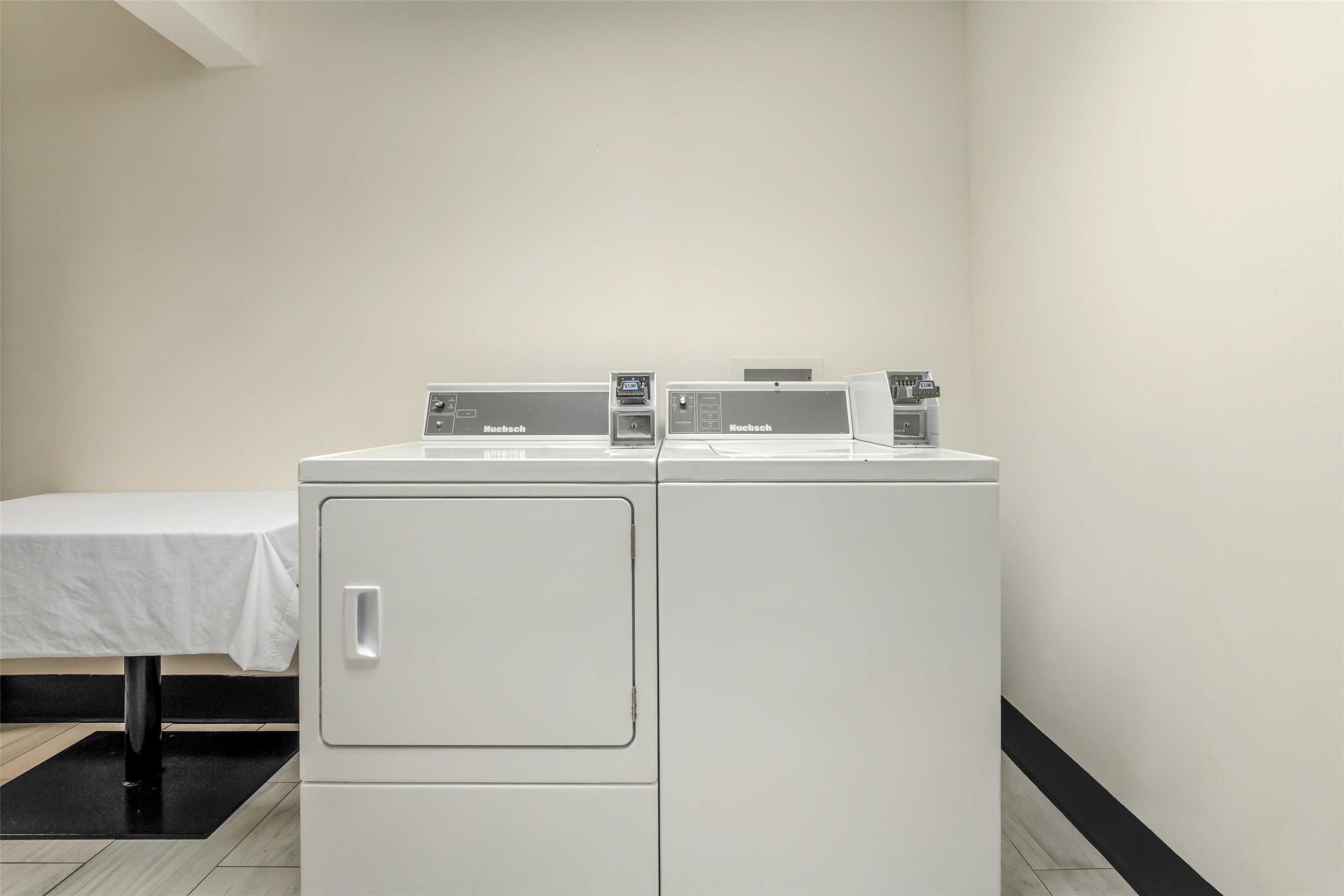 A laundry room with two stacked front-loading washing machines and a table with a white tablecloth.
