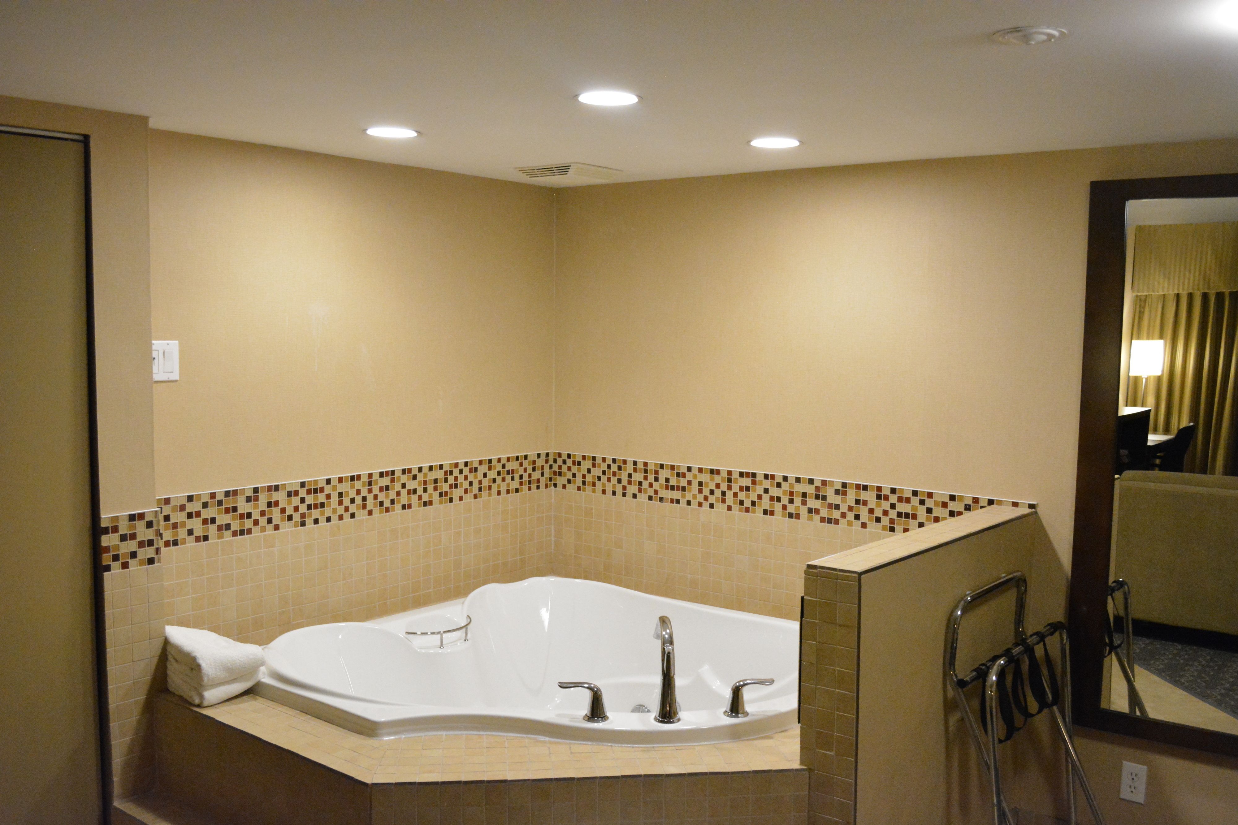 A bathroom with a large bathtub, a mirror, and a towel rack.