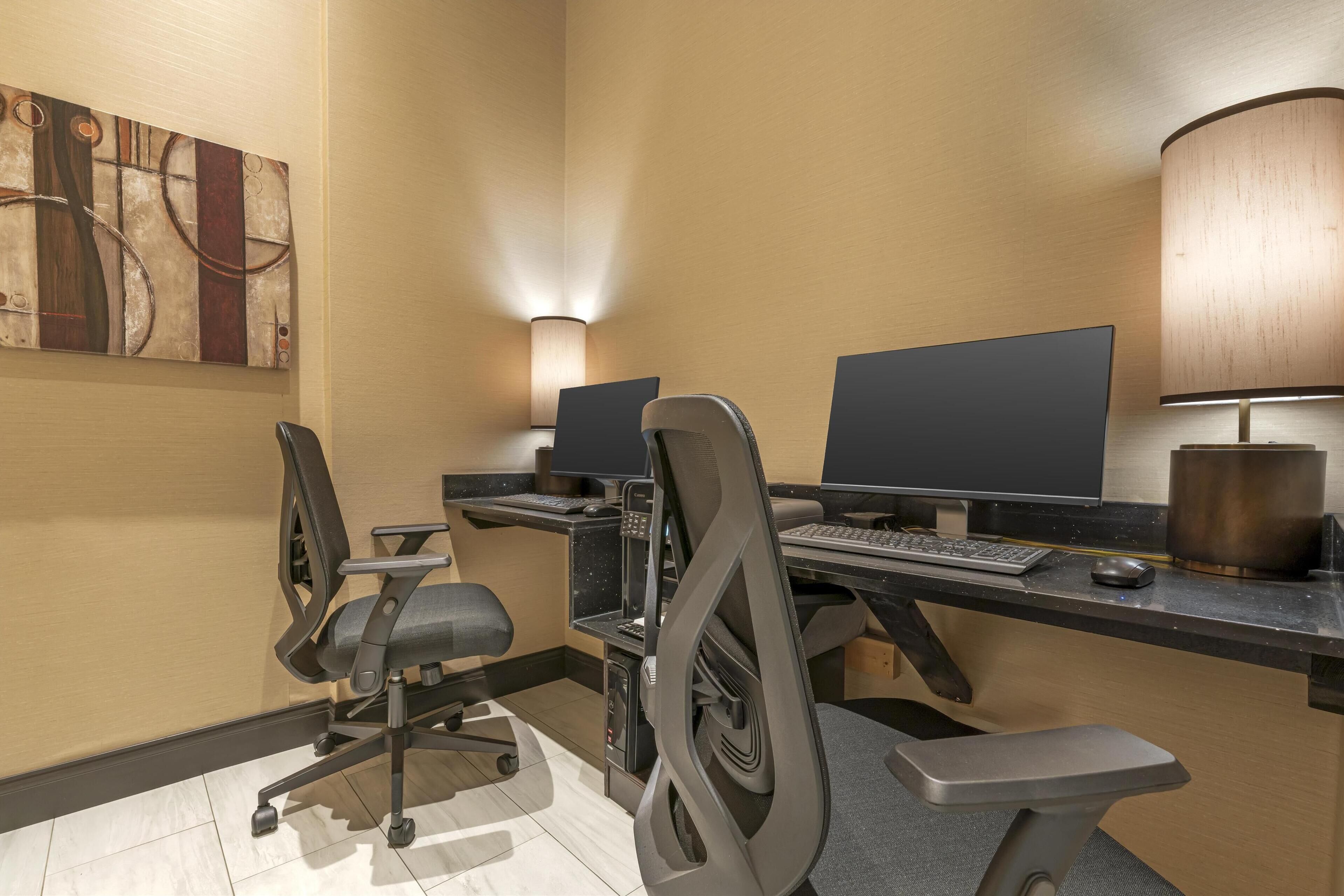 Ein moderner Arbeitsplatz mit zwei Schreibtischen, ergonomischen Stühlen und einem großen abstrakten Gemälde an der Wand.