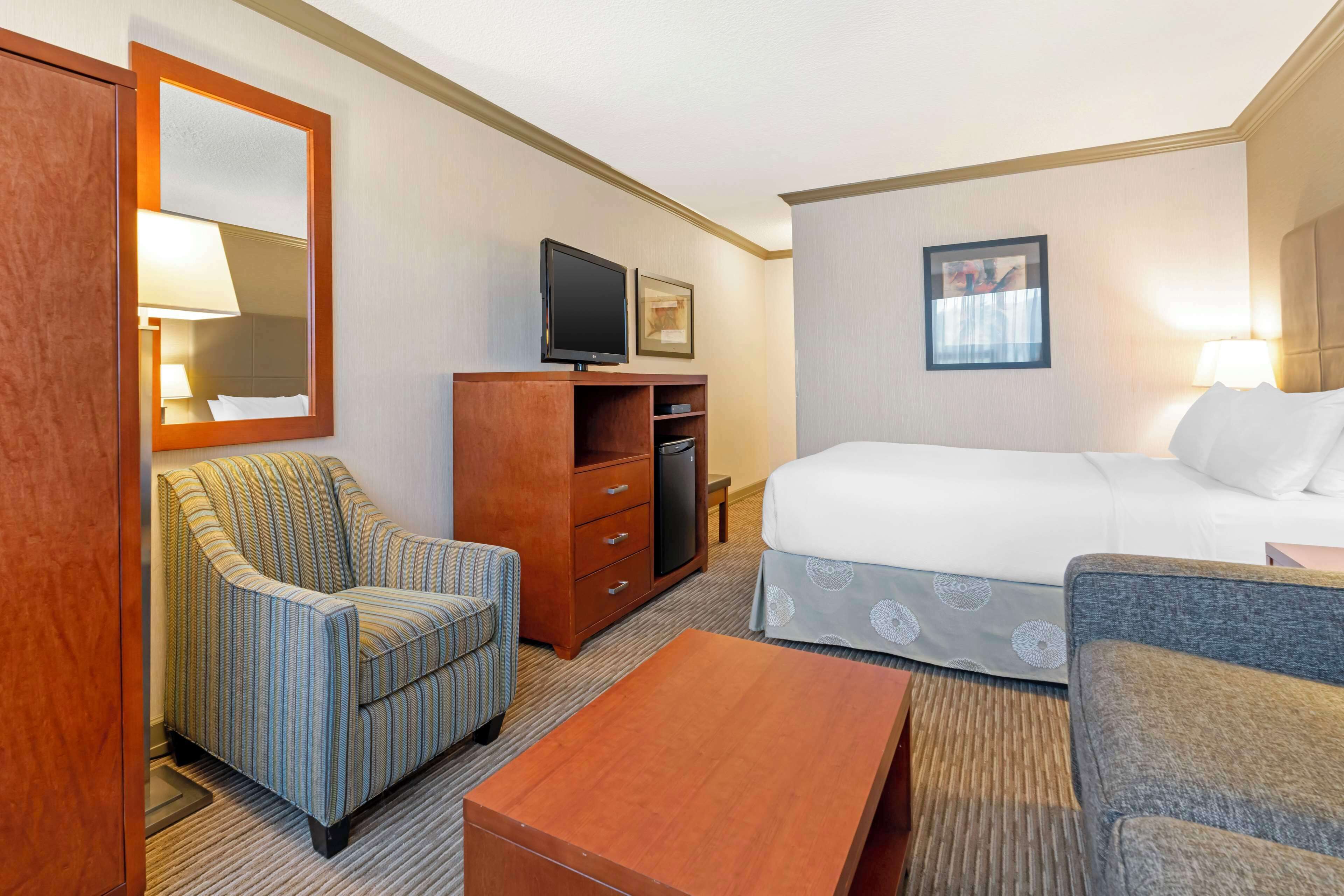 A hotel room with a bed, a television, a desk, and a chair.