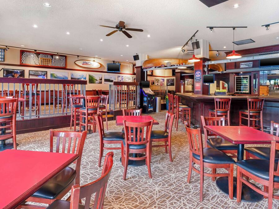 Een restaurant met houten tafels en stoelen, een bar en een plafondventilator.
