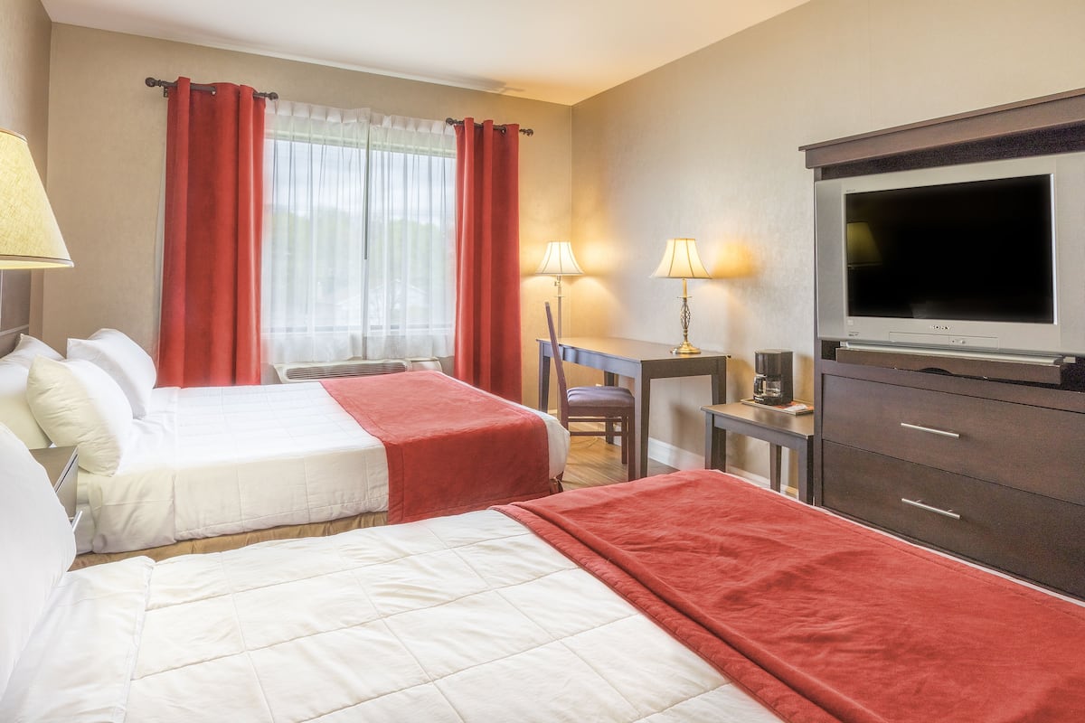 A hotel room with two beds, a desk, a TV, and a chair.