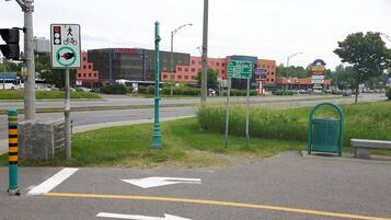 A hotel with a modern glass facade, a bike lane, and directional signs for nearby attractions.