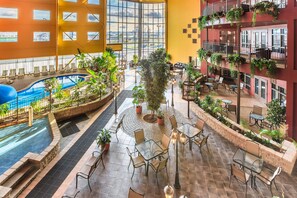 Un amplio atrio interior con piscina, zona de estar al aire libre y varios balcones con plantas.