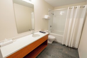A bathroom with a sink, mirror, toilet, and shower.