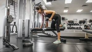 Ein Fitnessraum mit Krafttrainingsgeräten, darunter Hanteln und eine Bank.