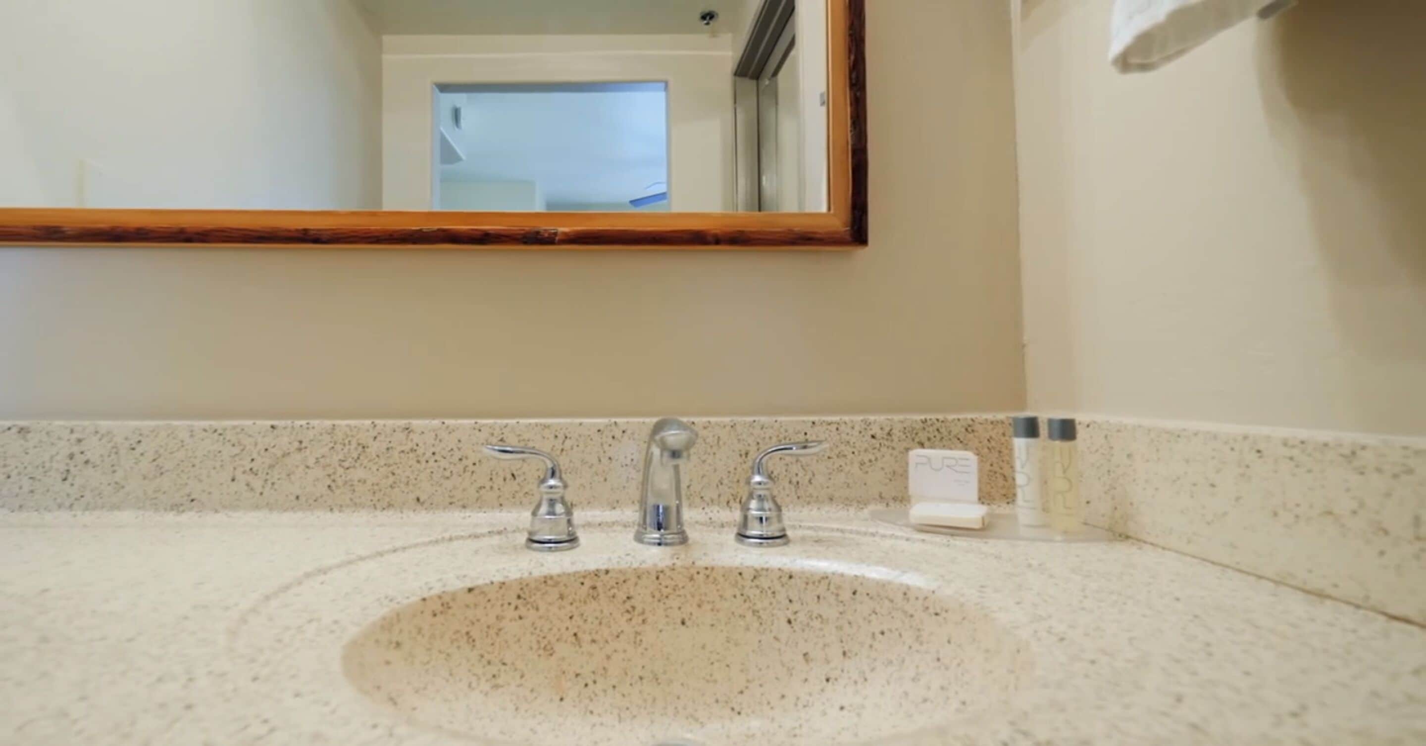 A bathroom with a granite countertop, a sink, and a mirror.