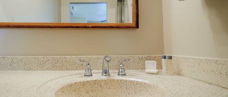A bathroom with a granite countertop, a sink, and a mirror.