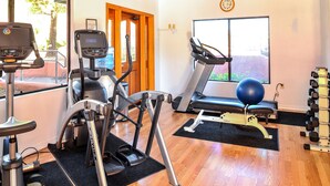 Gimnàs amb màquines cardiovasculars, una bicicleta estatica, una màquina d'esquí i una pilota d'exercici blava, i un conjunt de peses.