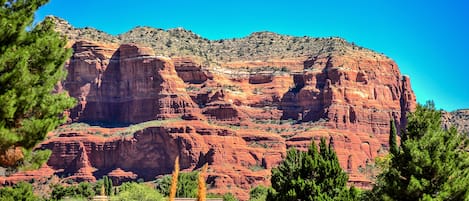 Un paysage montagneux caractérisé par des formations rocheuses rouges et une végétation verdoyante.